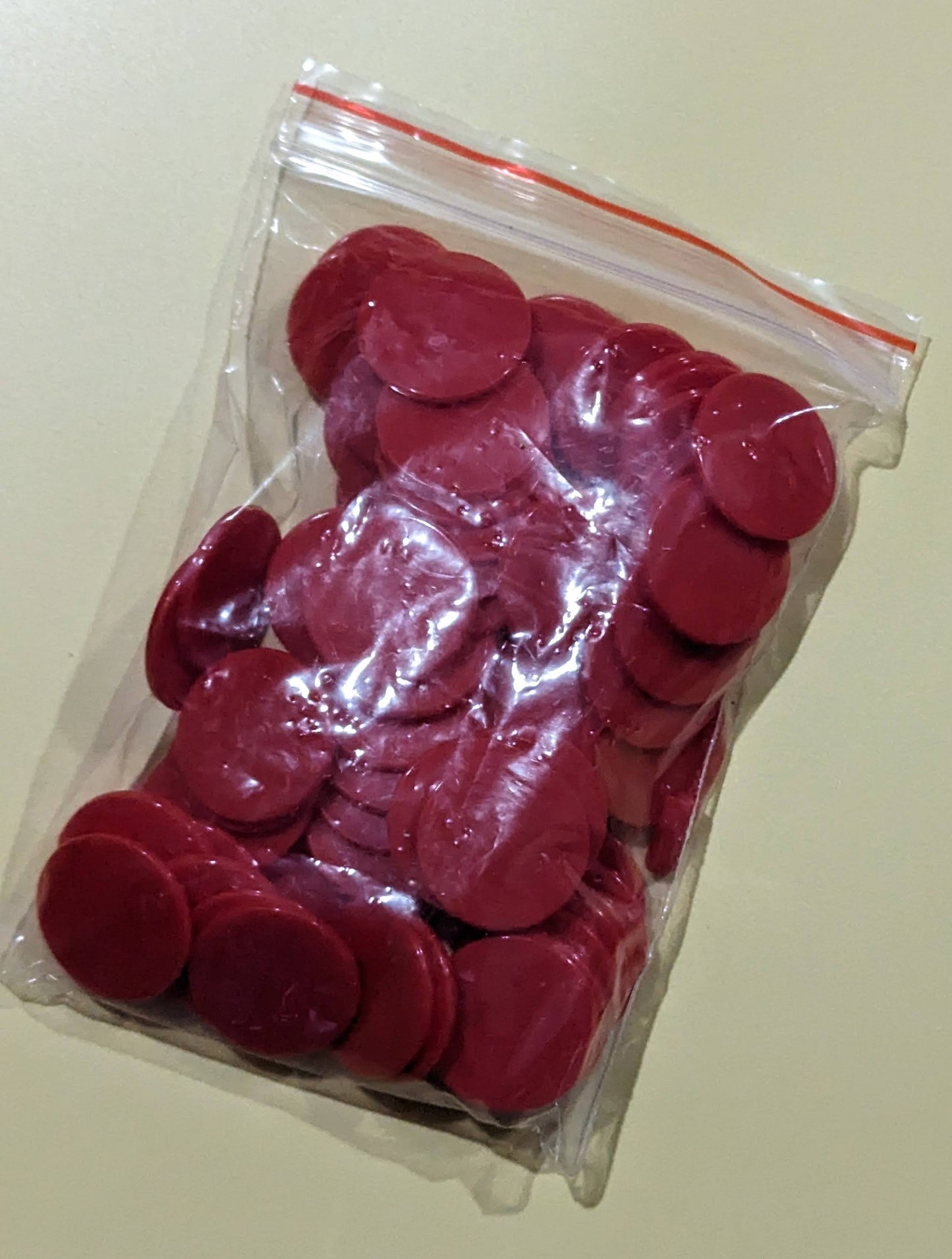 Red plastic chips for Aleph Bet Bingo game in a clear plastic bag.